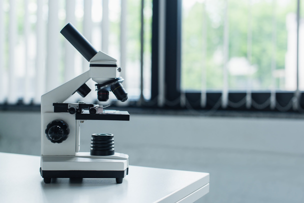 Microscope on white table in blurred laboratory  - Foto, Imagen
