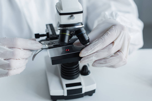 Cropped view of scientist in latex gloves using microscope in lab  - Φωτογραφία, εικόνα
