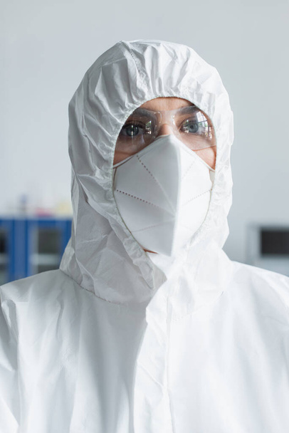 Portrait of scientist in hazmat suit and goggles looking at camera in lab  - Zdjęcie, obraz