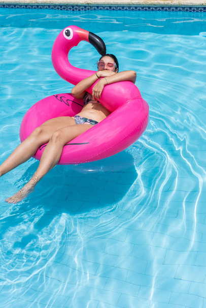 vrouw ontspannen, zweven in opblaasbare ring in zonnige zomer zwembad - Foto, afbeelding