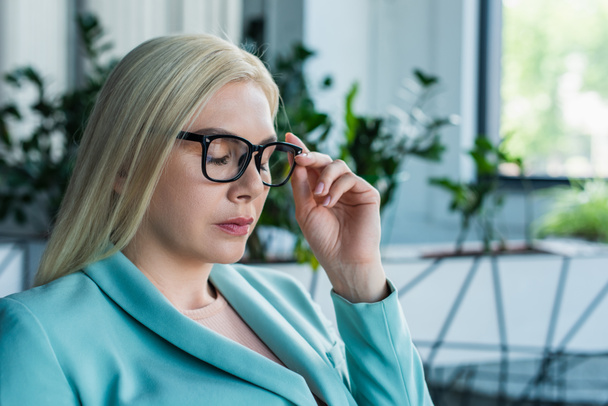 Blonde psychologist holding eyeglasses in consultation room  - Zdjęcie, obraz