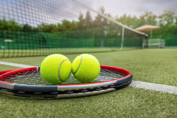 tennis racket and balls on synthetic grass outdoor court - Fotó, kép