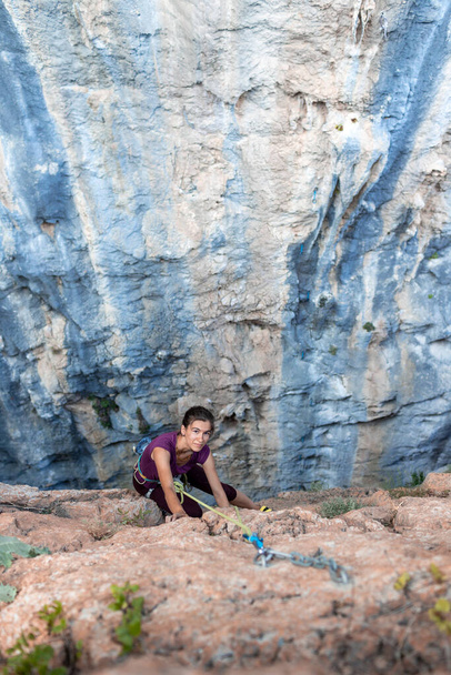 ορειβάτης κοριτσιών. Ένα κορίτσι σκαρφαλώνει σε μια πέτρα χρησιμοποιώντας εξοπλισμό και ένα σχοινί. ενεργό αθλητισμό και υπαίθρια αναψυχή - Φωτογραφία, εικόνα