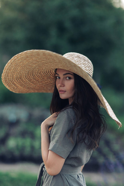 Portrait of young woman in wide-brimmed hat during walking on meadow. - Fotoğraf, Görsel