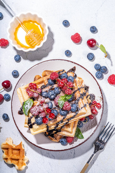 Sweet waffles with berry.  Homemade summer breakfast belgian waffles with raspberries, blueberries, strawberry honey and chocolate dip sauce,  copy space - Photo, image