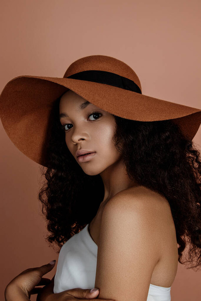 Close up portrait of sensual young female in hat. Clean skin. Healthy care. Portrait of beautiful african american in hat isolated. Studio shoot. Portrait of beauty girl model with natural make up - Zdjęcie, obraz