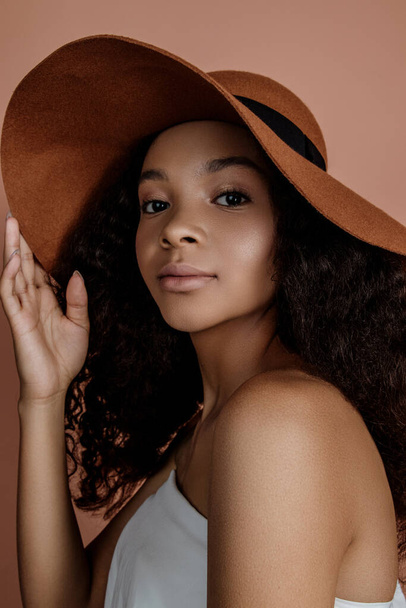 Close up portrait of sensual young female in hat. Clean skin. Healthy care. Portrait of beautiful african american in hat isolated. Studio shoot. Portrait of beauty girl model with natural make up - Zdjęcie, obraz