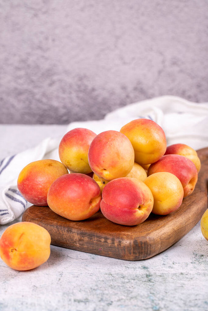 Fresh apricots. Ripe apricots in wooden serving platter on stone background. Bulk apricots. close up - Fotó, kép