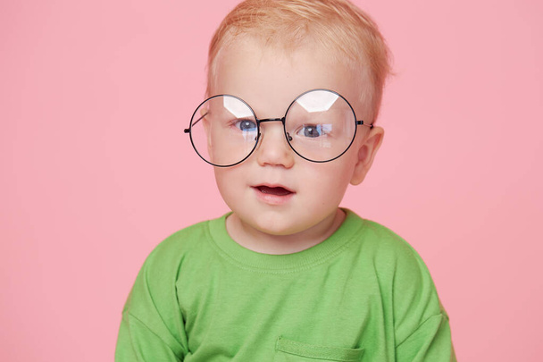 Portrait of male baby boy on pink background wearing glasses and looking at the camera. Smart baby concept - Foto, imagen