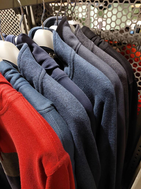 hoodies op hangers in de winkel. Handel in warme kleding in het retailnetwerk. Close-up - Foto, afbeelding