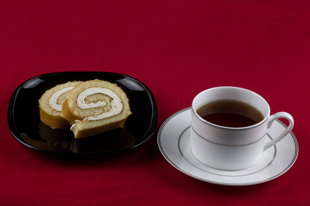 Чашка чаю і шматочків торта на тканині червоного столу
 - Фото, зображення