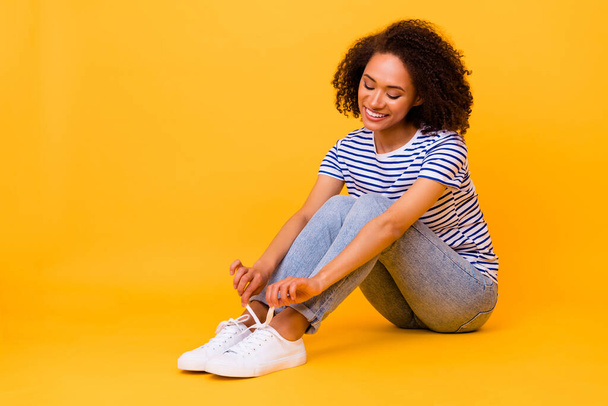 Full body portrait of charming cute person sit floor tying shoe laces isolated on yellow color background. - Fotoğraf, Görsel