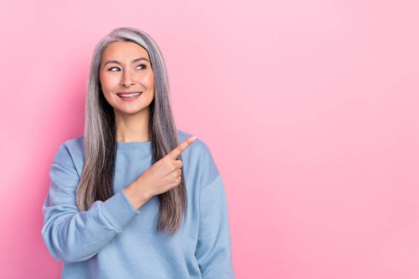 Photo of cute adorable lady pensioner dressed blue pullover looking pointing empty space isolated pink color background. - Φωτογραφία, εικόνα