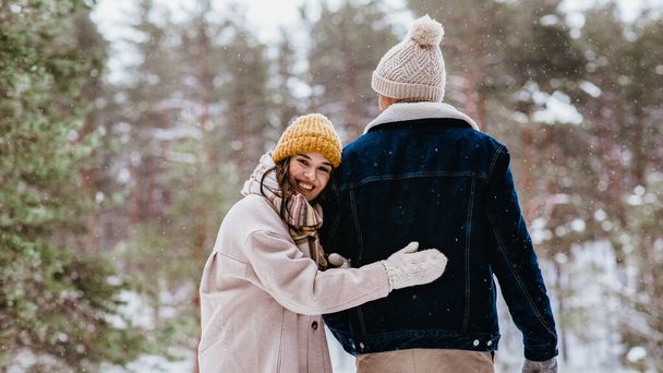 people, love and leisure concept - happy smiling couple walking in winter forest - 写真・画像