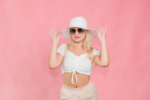 a young girl in a white hat and glasses poses on a pink background - Fotografie, Obrázek
