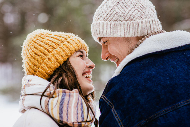 people, love and leisure concept - happy smiling couple looking at each other in winter forest - Фото, изображение