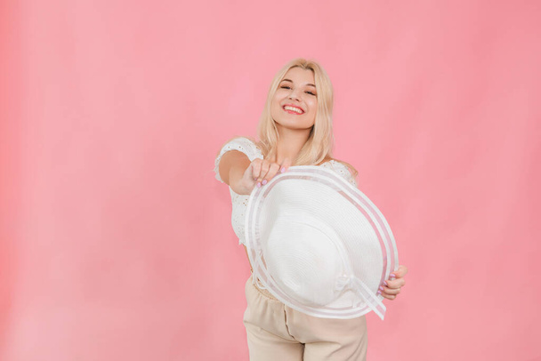 молода дівчина в білому капелюсі і одязі позує на рожевому фоні
 - Фото, зображення