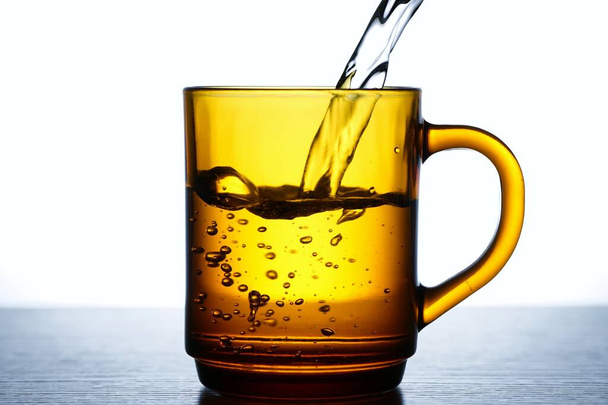 Φωτογραφίες ρίχνετε νερό σε ένα τσάι ή καφέ γυαλί - Φωτογραφία, εικόνα