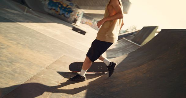 Actieve skateboarder probeert truc op de helling en faalt buiten. Closeup mannelijke tiener doet truc op skate board in de lucht. Casual jongen maakt oefening op schaatsen in de stedelijke ruimte. Extreme man levensstijl concept - Foto, afbeelding