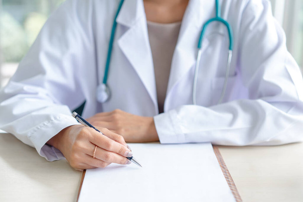 Female doctor writing on medical paper at a clinic. - Photo, Image