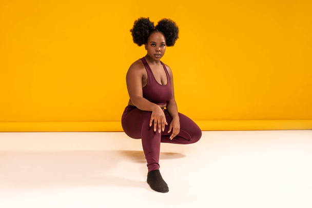 Happy plus size woman posing in sporty black fashionable clothes, smiling to the camera. Copy space. Sports and weight loss concept. Studio shot. Full length photo - Fotó, kép