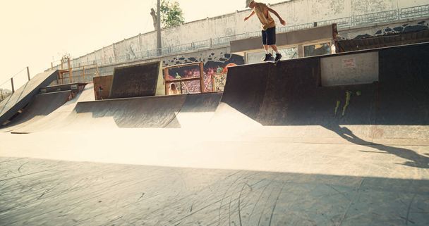 Tiener oefent stuntsprong op skateboard in de stedelijke ruimte. Extreme mannelijke ruiter bereidt zich voor op skateboarden competitie buiten. Actieve jongen die tijd doorbrengt met boord in het skatepark. Sport concept. - Foto, afbeelding