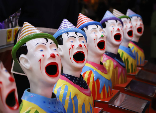 Μια σειρά από πολύχρωμους κλόουν με ανοιχτά στόματα, μια ατραξιόν σε ένα πανηγύρι, κοντά - Φωτογραφία, εικόνα