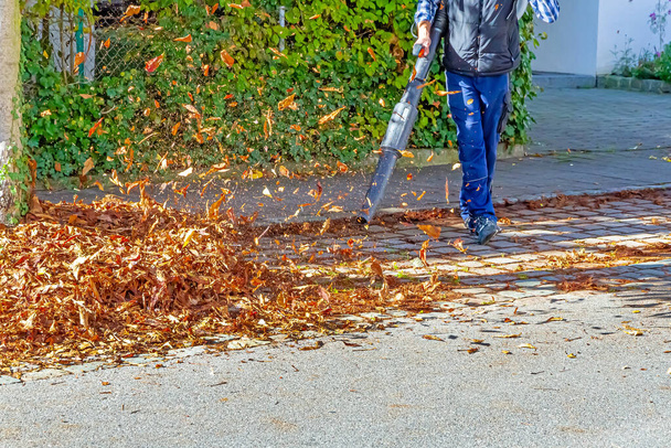 Worker on a street in autumn with a leaf blower - Fotoğraf, Görsel