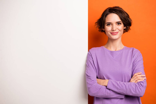 Portrait of positive charming lady crossed arms empty space blank isolated on orange color background. - 写真・画像