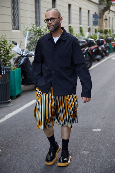 MILAN, ITALY - JUNE 18, 2022: Man with orange, white and black striped shorts before Versace fashion show, Milan Fashion Week street style - Valokuva, kuva