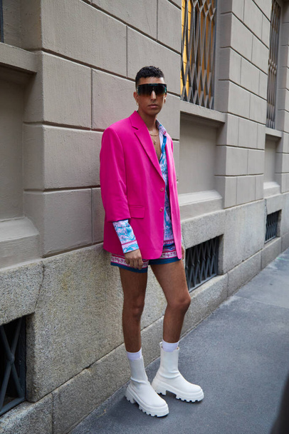 MILAN, ITALY - JUNE 18, 2022: Man with pink jacket, sunglasses and white boots before Versace fashion show, Milan Fashion Week street style - Fotó, kép