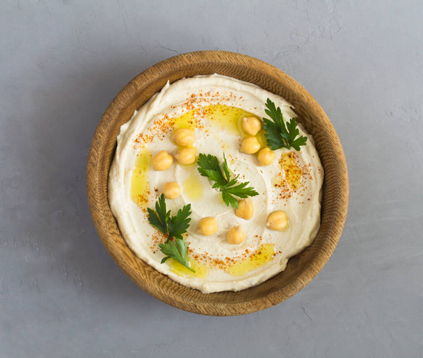 Top view of hummus in the brown bowl on the gray cement background. Closeup. - Photo, Image