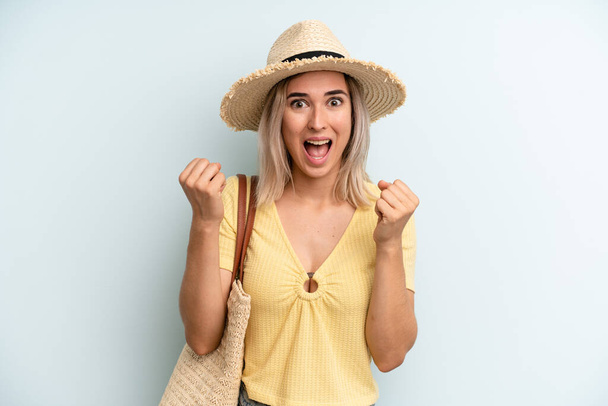 blonde woman feeling shocked,laughing and celebrating success. summer concept - Фото, изображение