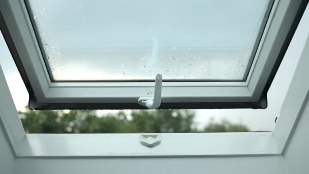 Vista cercana de las gotas de lluvia que caen desde el marco de la ventana del tragaluz durante la lluvia. Imágenes de FullHD - Metraje, vídeo