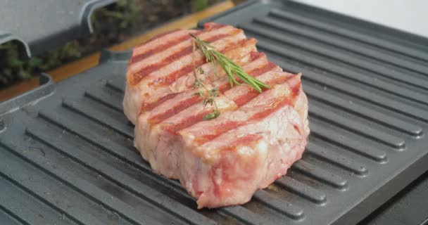 Delicious juicy beef steak with rosemary is cooked on an electric grill. Aged prime rare roast grilling tenderloin fresh marble tenderness beef. Prime beef fry on electric roaster. - Video, Çekim