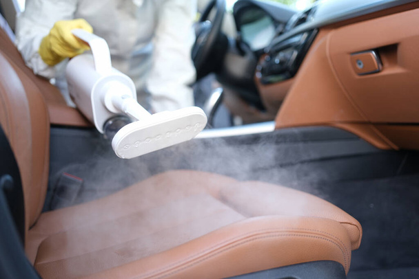 Limpieza de vapor y desinfección de interiores y asientos de coche con limpiador de vapor. Concepto de limpieza interior del coche - Foto, imagen