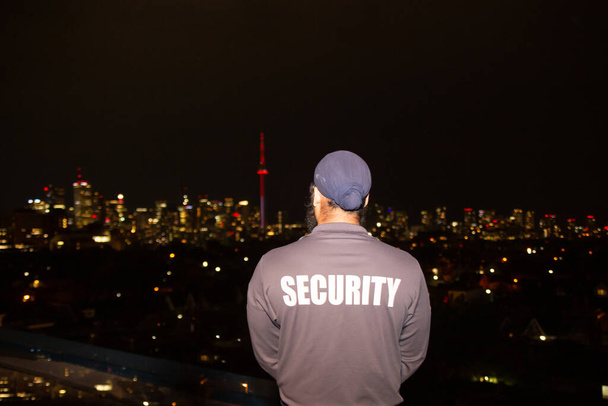Security guard patrolling city streets at night - 写真・画像