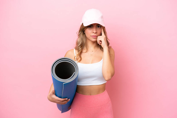 Young sport woman going to yoga classes while holding a mat thinking an idea - Photo, image