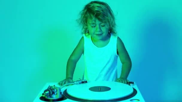 A cute djing small girl mixing vinyl on record player with coloured disco lighting - 映像、動画