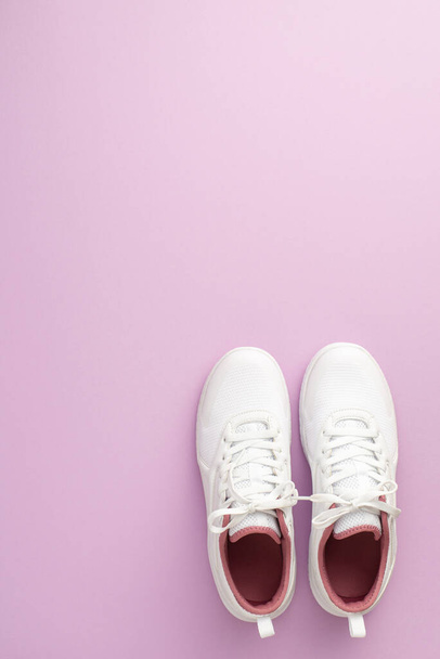 Sports concept. Top view vertical photo of white sneakers on isolated pastel lilac background with copyspace - Foto, Bild