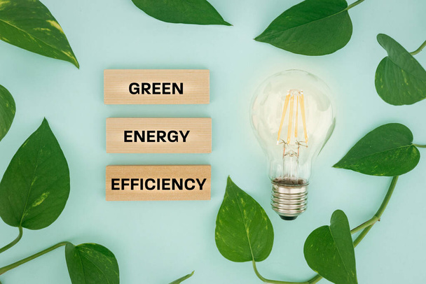 Лампочка в окружении листьев и текста на деревянных блоках, Зеленая энергоэффективность, Экологическая система, Креативная концепция, Современные источники энергии, яркий фон, плоский уголок - Фото, изображение