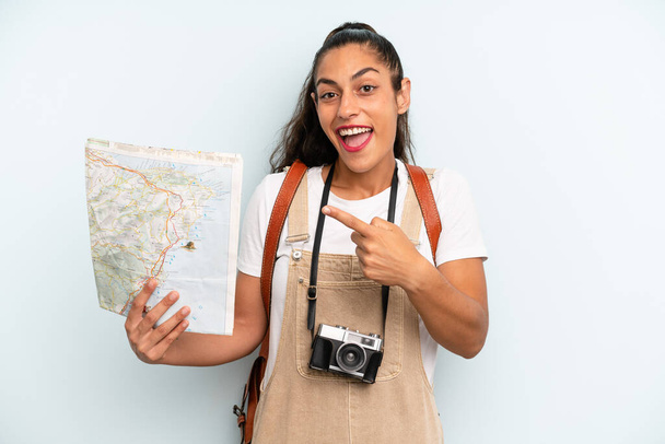 hispanic woman looking excited and surprised pointing to the side. tourist with a map - Zdjęcie, obraz