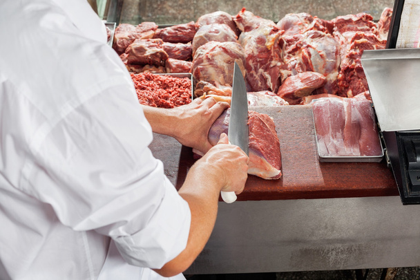 Обрезанный образ мужского мясника резки мяса
 - Фото, изображение