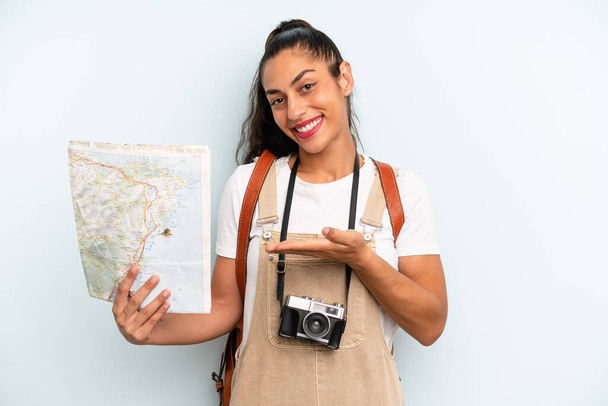 hispanic woman smiling cheerfully, feeling happy and showing a concept. tourist with a map - Foto, afbeelding