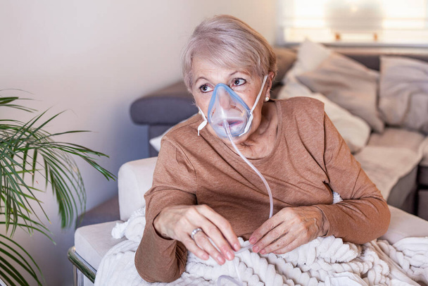 Beteg idős nő oxigénmaszkos inhalációval, tüdőgyulladás, koronavírus világjárvány. Oxigénmaszkot viselő és kezelésen áteső idős beteg nő. idős nő kovid 19 - Fotó, kép
