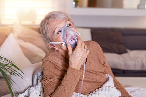 Άρρωστη ηλικιωμένη γυναίκα που κάνει εισπνοή, η ιατρική είναι το καλύτερο φάρμακο. Μια ηλικιωμένη γυναίκα που φοράει μάσκα οξυγόνου και υποβάλλεται σε θεραπεία. Ανώτερη γυναίκα με αναπνευστήρα - Φωτογραφία, εικόνα