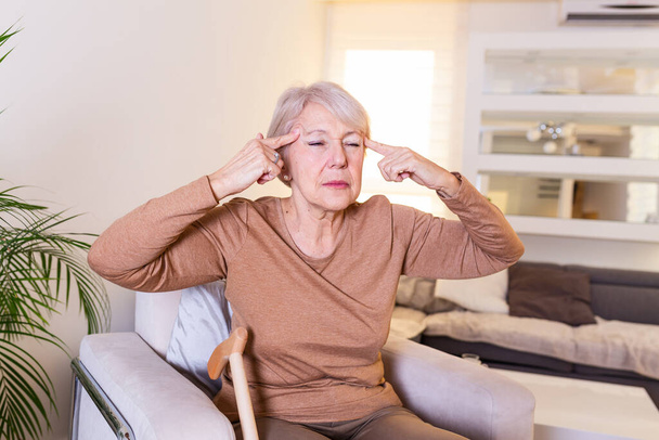 Γυναίκα που υποφέρει από άγχος ή πονοκέφαλο, γκρινιάζει από τον πόνο. Ηλικιωμένη γυναίκα με ημικρανία δεν αισθάνεται καλά. Πορτρέτο μιας ελκυστικής ηλικιωμένης γυναίκας με πονοκέφαλο, αίσθημα πόνου - Φωτογραφία, εικόνα