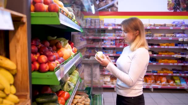 Gyümölcs a boltban. Zöldségek osztálya a szupermarketben. Egy lány gyümölcsöt vesz. Természetes termékek értékesítése. ECO-termékek. - Felvétel, videó