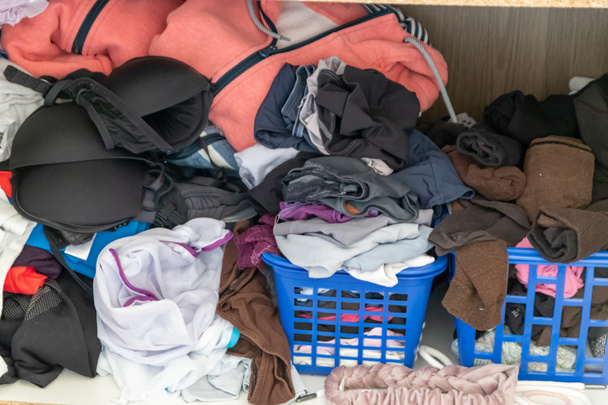 Хаотический гардероб и небрежный шкаф показывает много нарядов женщины с пристрастием к покупкам и много одежды, как пуловеры, рубашки и брюки, как смятое белье хранится в грязной куче моды - Фото, изображение