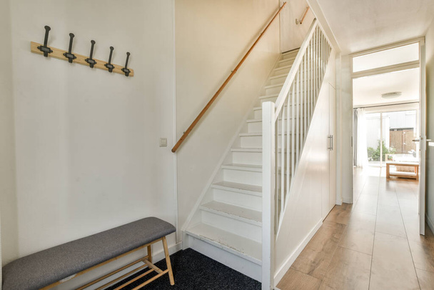 Pasillo blanco con escalera de madera que conduce al segundo piso de un moderno apartamento de lujo con diseño interior minimalista - Foto, Imagen
